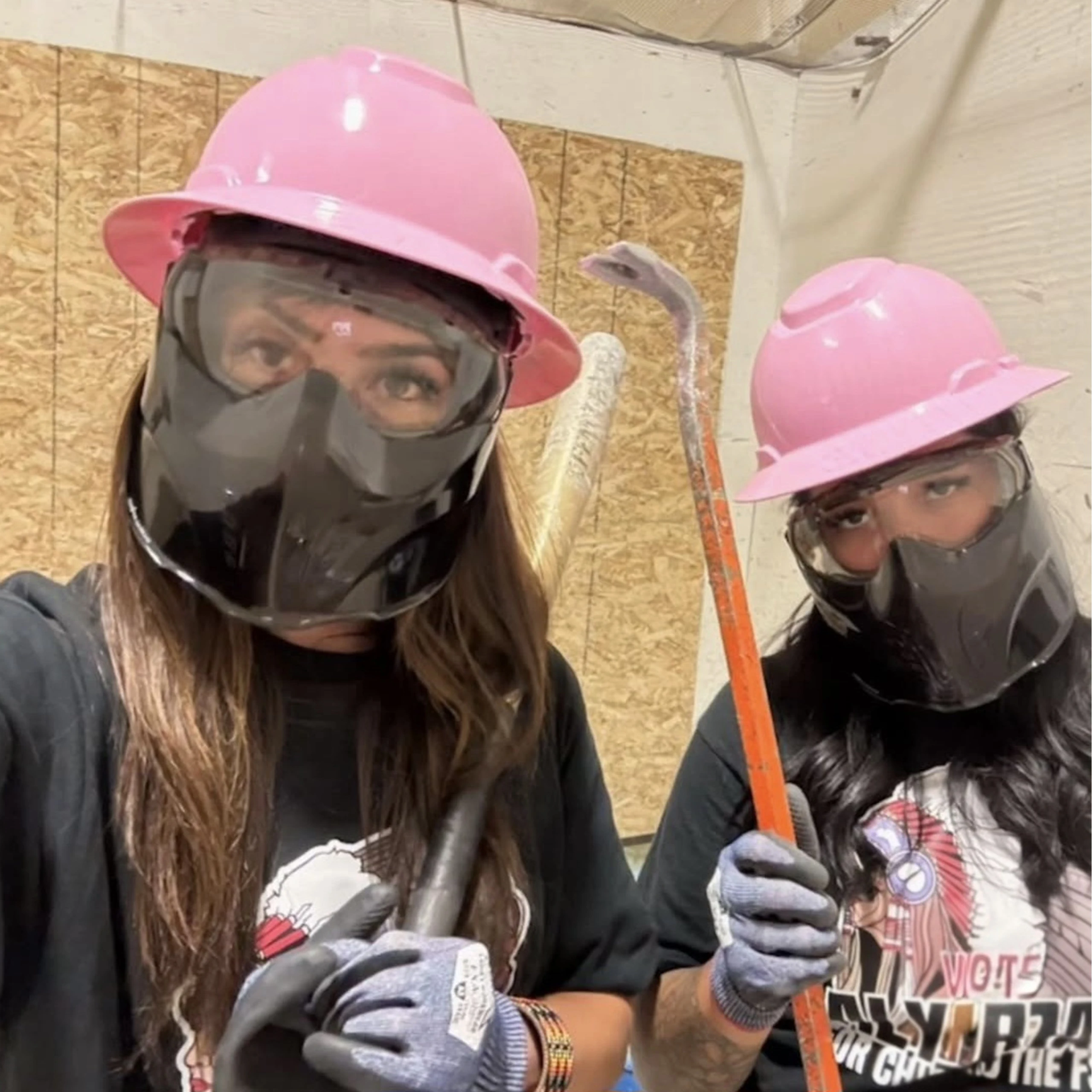 Two women wearing protective gear in a smash room